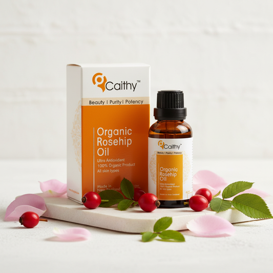 Caithy's Organic Rosehip Oil bottle and box with rosehip berries and rose petals on white stone